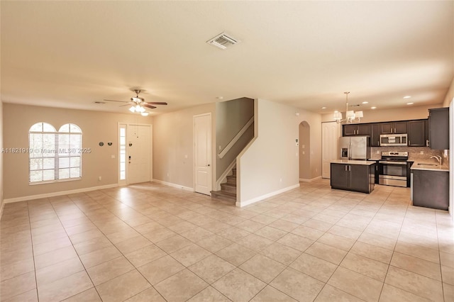 3809 Aspen Leaf Dr, Boynton Beach, FL 33436 - unfurnished living room featuring light tile patterned floors, arched walkways, a chandelier, stairway, and a ceiling fan