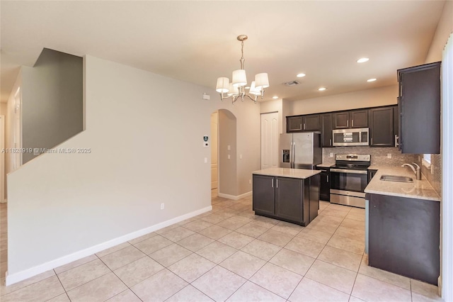 3809 Aspen Leaf Dr, Boynton Beach, FL 33436 - kitchen with appliances with stainless steel finishes, arched walkways, a kitchen island, a chandelier, and light tile patterned floors