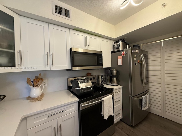 15400 SW 284th St Unit 1308, Homestead, FL 33033 - kitchen with appliances with stainless steel finishes, white cabinetry, light countertops, dark wood-style flooring, and a textured ceiling