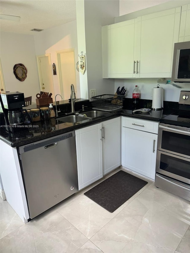 470 NW 102nd Ter, Pembroke Pines, FL 33026 - kitchen with stainless steel appliances, a peninsula, dark stone counters, and white cabinets