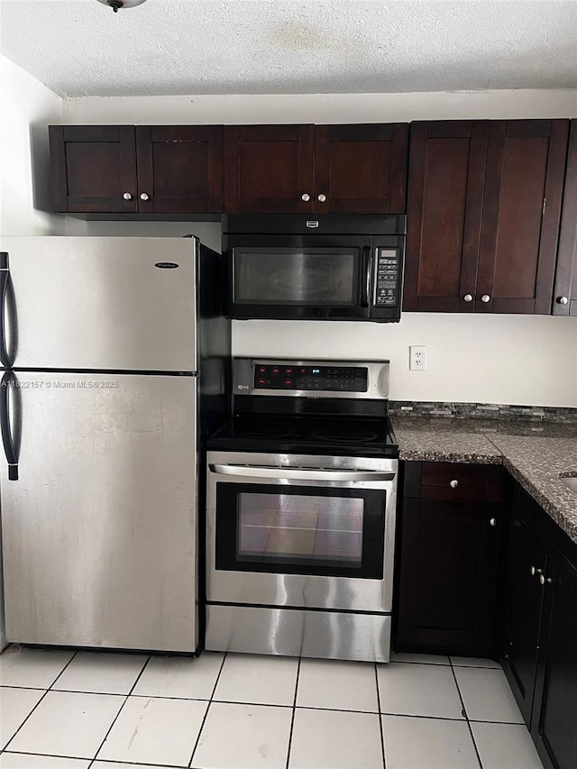 498 NW 165th St Rd Unit D303, Miami, FL 33169 - kitchen with appliances with stainless steel finishes, dark countertops, light tile patterned flooring, dark brown cabinets, and a textured ceiling