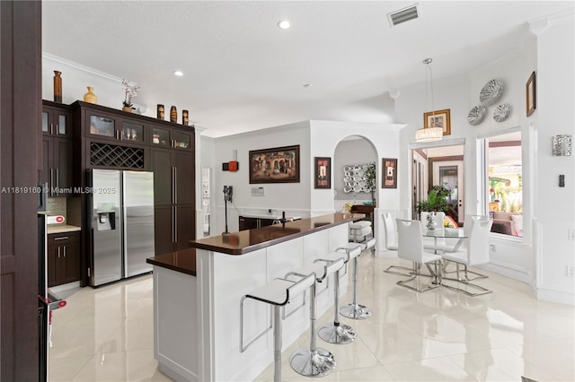 16601 SW 87th Ct, Palmetto Bay, FL 33157 - kitchen with stainless steel refrigerator with ice dispenser, ornamental molding, a breakfast bar, light tile patterned flooring, and recessed lighting