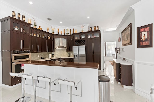 16601 SW 87th Ct, Palmetto Bay, FL 33157 - kitchen with stainless steel appliances, crown molding, light tile patterned flooring, wall chimney exhaust hood, and a kitchen bar