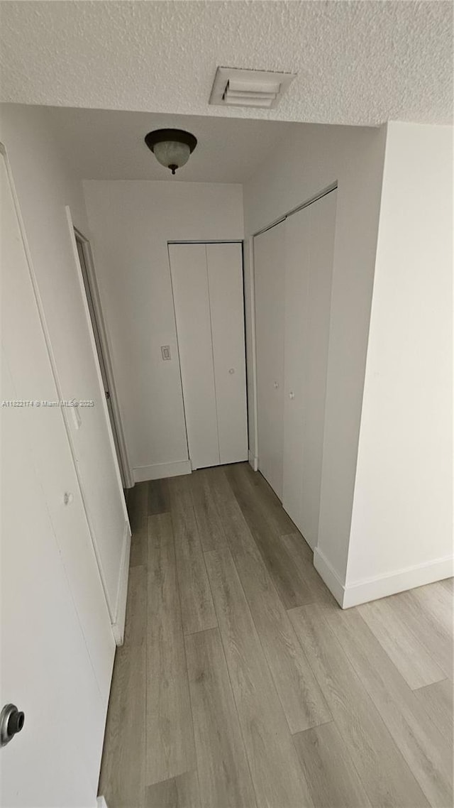 608 NE 2nd St Unit 133, Dania Beach, FL 33004 - unfurnished bedroom with a textured ceiling, light wood-type flooring, and multiple closets