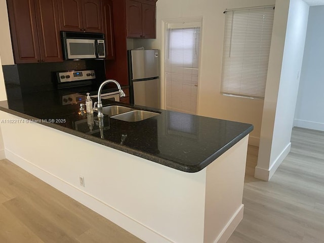 608 NE 2nd St Unit 133, Dania Beach, FL 33004 - kitchen with stainless steel appliances, a peninsula, light wood-style flooring, and dark stone countertops