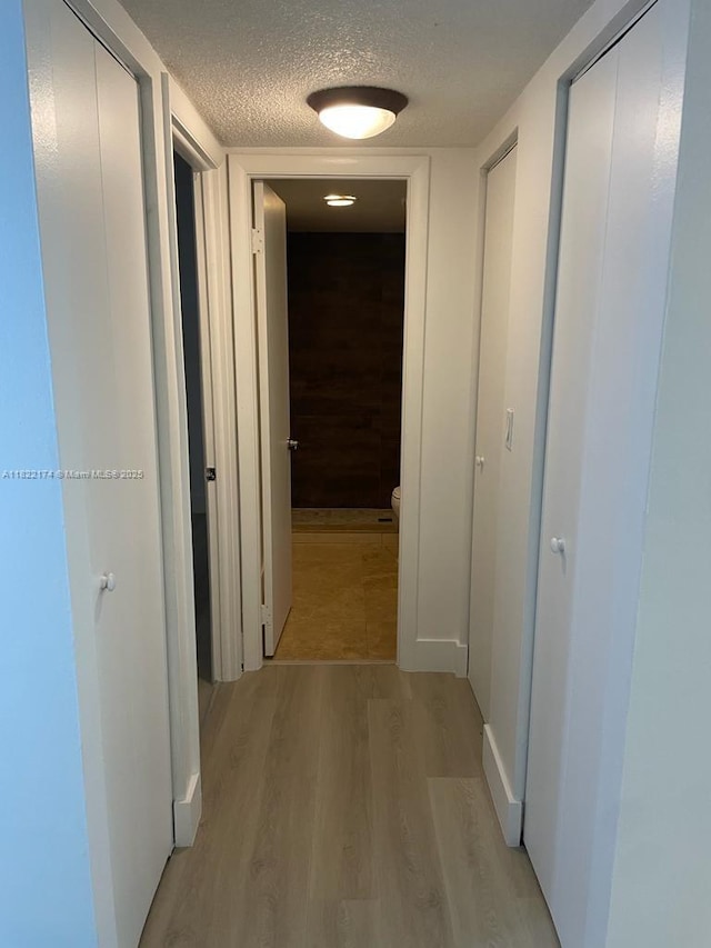 608 NE 2nd St Unit 133, Dania Beach, FL 33004 - hallway with light wood-style flooring and a textured ceiling