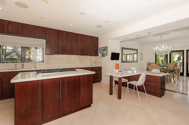 6535 Allison Rd, Miami Beach, FL 33141 - kitchen featuring gas cooktop, a kitchen island, backsplash, plenty of natural light, and ornamental molding
