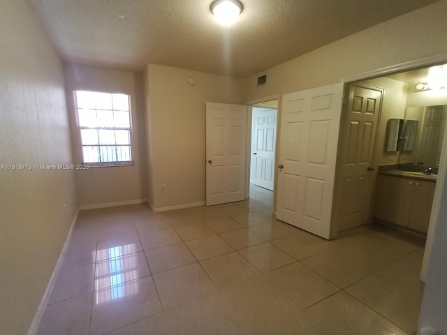 503 Belmont Ln Unit 503, North Lauderdale, FL 33068 - unfurnished bedroom featuring light tile patterned floors, a textured ceiling, and ensuite bath