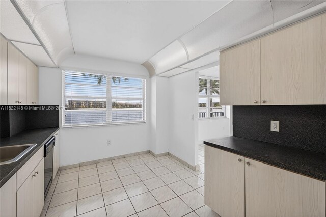 2851 NE 183rd St Unit 216E, Aventura, FL 33160 - kitchen featuring dark countertops, dishwashing machine, decorative backsplash, light tile patterned floors, and light brown cabinets