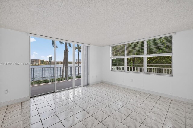 2851 NE 183rd St Unit 216E, Aventura, FL 33160 - spare room featuring a water view, a textured ceiling, plenty of natural light, and light tile patterned floors