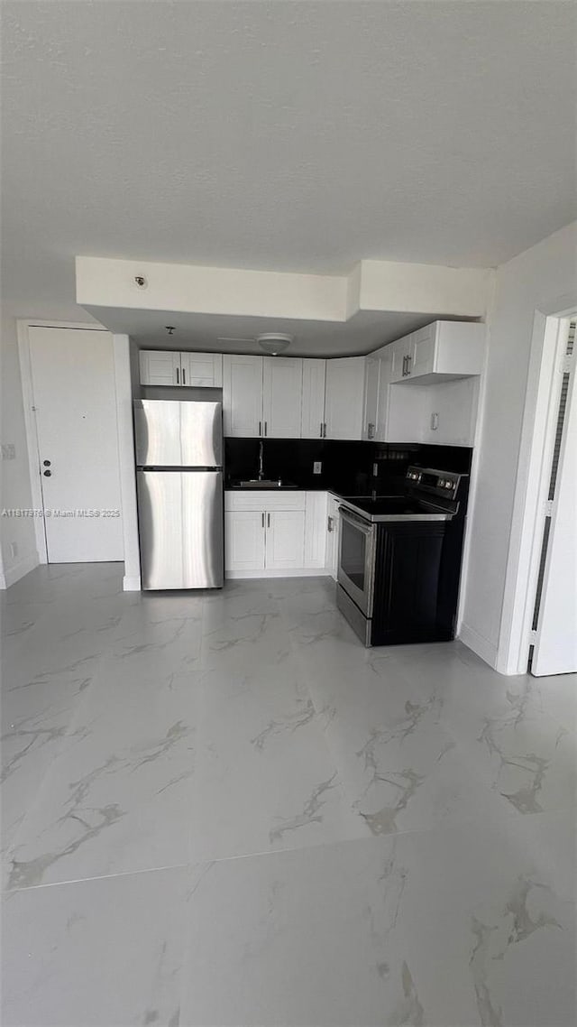 16450 NW 2nd Ave Unit 409, Miami, FL 33169 - kitchen featuring freestanding refrigerator, range with electric stovetop, light marble finish flooring, white cabinetry, and a textured ceiling