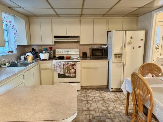 2671 SW 107th Ave, Miami, FL 33165 - kitchen featuring white appliances, under cabinet range hood, a paneled ceiling, cream cabinetry, and light countertops