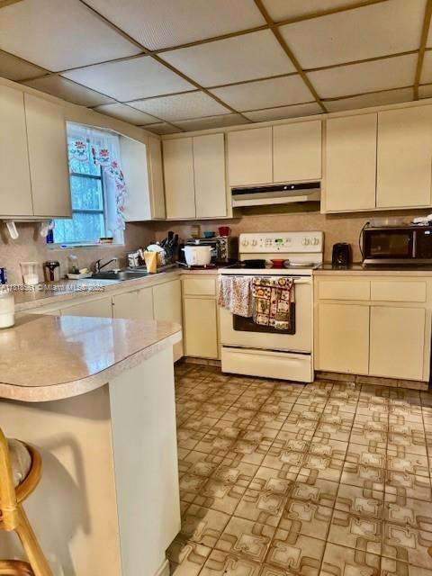 2671 SW 107th Ave, Miami, FL 33165 - kitchen featuring white electric range oven, under cabinet range hood, a kitchen bar, light countertops, and a peninsula