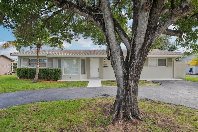1700 SW 5th Ave, Pompano Beach, FL 33060 - ranch-style home featuring a front yard, a tiled roof, asphalt driveway, and stucco siding