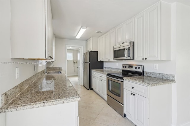 1700 SW 5th Ave, Pompano Beach, FL 33060 - kitchen with stainless steel appliances, light tile patterned floors, white cabinetry, and light stone countertops