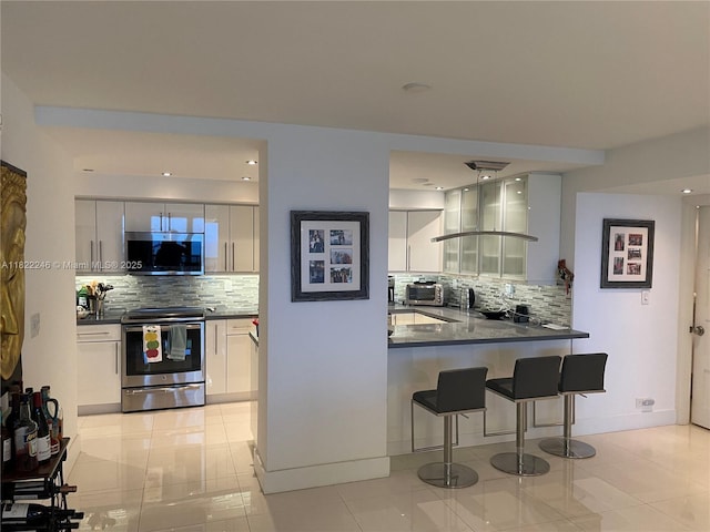 6039 Collins Ave Unit 1525, Miami Beach, FL 33140 - kitchen with stainless steel appliances, dark countertops, backsplash, and a breakfast bar
