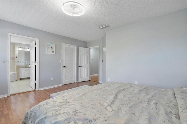 19257 NW 14th St, Pembroke Pines, FL 33029 - bedroom featuring wood finished floors, a textured ceiling, and connected bathroom