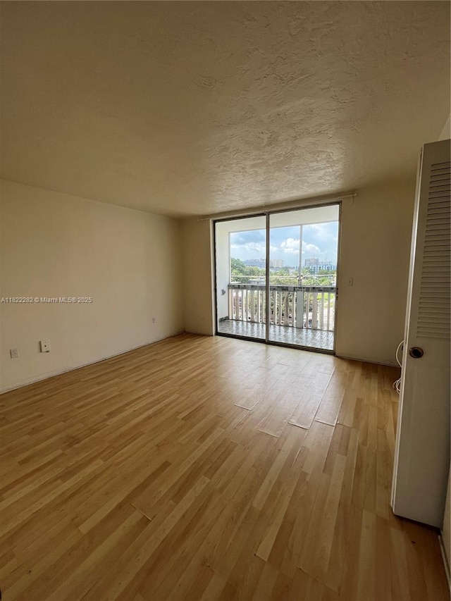 1475 NE 125th Ter Unit 511B, North Miami, FL 33161 - spare room featuring light wood-type flooring, a wall of windows, and a textured ceiling