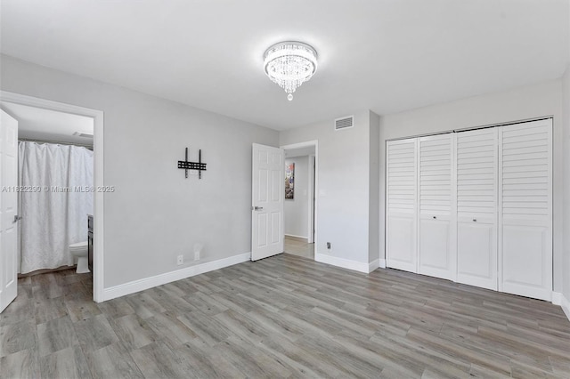 7225 Promenade Dr Unit 102, Boca Raton, FL 33433 - unfurnished bedroom featuring light wood-style flooring, a chandelier, a closet, and connected bathroom