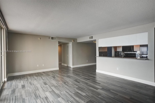 1200 Brickell Bay Dr Unit 2501, Miami, FL 33131 - unfurnished living room featuring a textured ceiling and dark wood-style floors