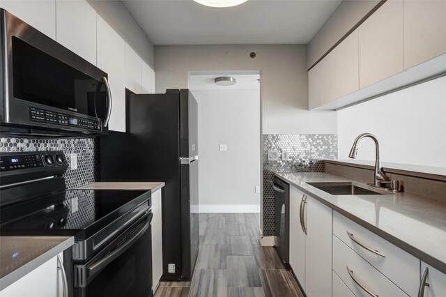 1200 Brickell Bay Dr Unit 2501, Miami, FL 33131 - kitchen with black range with electric cooktop, stainless steel microwave, white cabinets, backsplash, and wood tiled floors