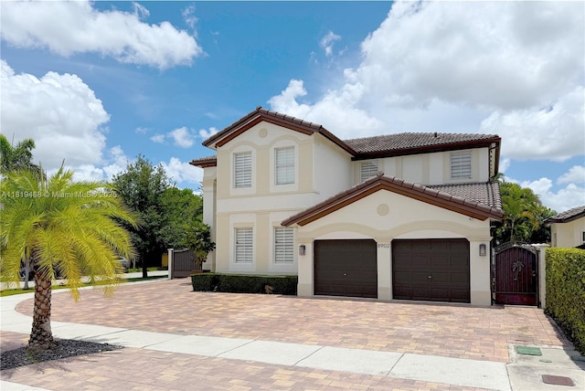 8902 NW 178th Ln, Hialeah, FL 33018 - mediterranean / spanish house featuring a tiled roof, a gate, stucco siding, and decorative driveway