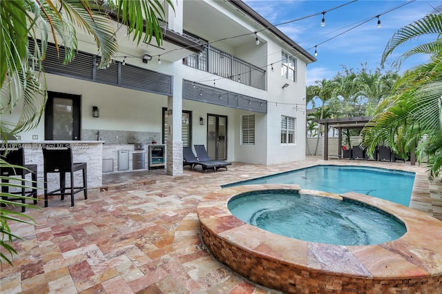 8902 NW 178th Ln, Hialeah, FL 33018 - view of pool featuring a pool with connected hot tub, a patio area, exterior bar, and an outdoor kitchen