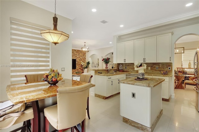 8902 NW 178th Ln, Hialeah, FL 33018 - kitchen with arched walkways, a peninsula, a kitchen island, tasteful backsplash, and crown molding