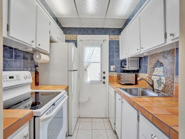 16901 NE 13th Ave Unit 110, Miami, FL 33162 - kitchen with white appliances, white cabinetry, tile countertops, backsplash, and light tile patterned flooring