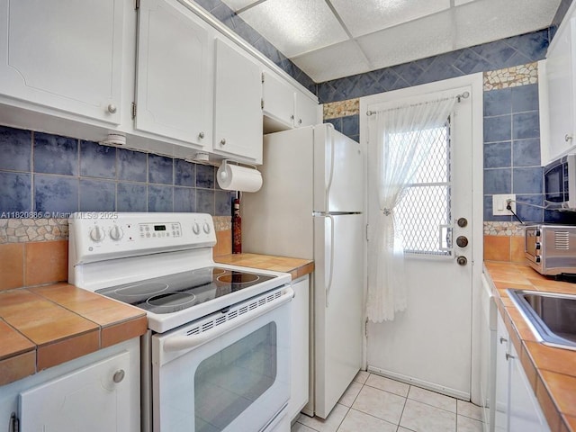 16901 NE 13th Ave Unit 110, Miami, FL 33162 - kitchen with white appliances, white cabinetry, decorative backsplash, light tile patterned floors, and tile countertops