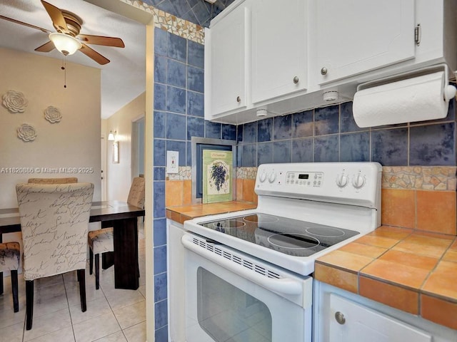 16901 NE 13th Ave Unit 110, Miami, FL 33162 - kitchen with electric range, tile counters, white cabinets, a ceiling fan, and tasteful backsplash