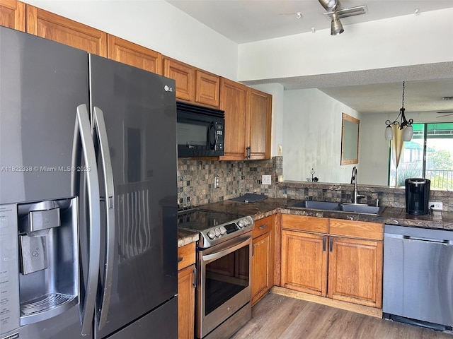 12666 NW 14th Pl Unit 12666, Sunrise, FL 33323 - kitchen with stainless steel appliances, brown cabinetry, decorative backsplash, light wood-style floors, and pendant lighting