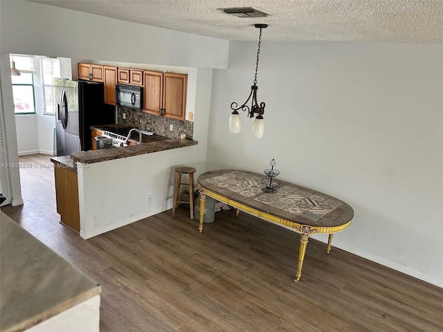 12666 NW 14th Pl Unit 12666, Sunrise, FL 33323 - kitchen with fridge with ice dispenser, black microwave, brown cabinetry, dark wood-type flooring, and a textured ceiling