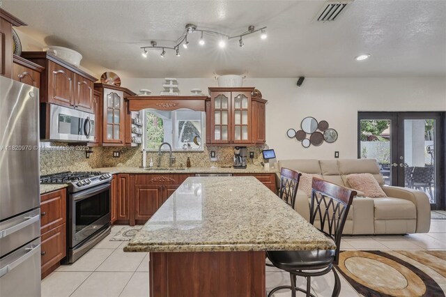 8981 NW 166th Ter, Miami Lakes, FL 33018 - kitchen with stainless steel appliances, light tile patterned floors, backsplash, a breakfast bar area, and glass insert cabinets