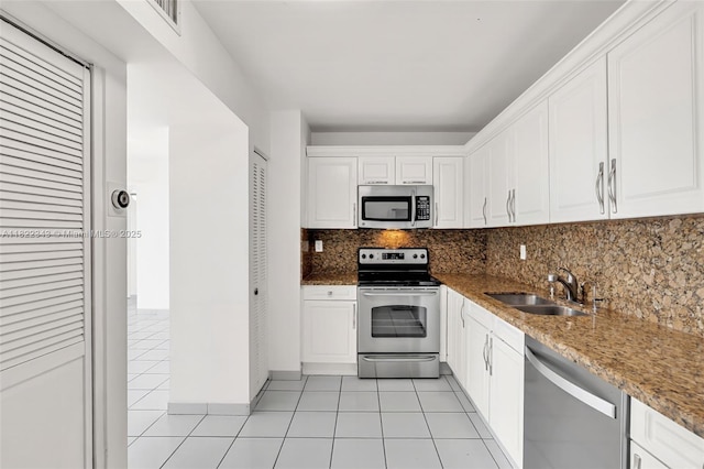 9341 Collins Ave Unit 705, Surfside, FL 33154 - kitchen with stainless steel appliances, white cabinetry, backsplash, light tile patterned flooring, and light stone counters
