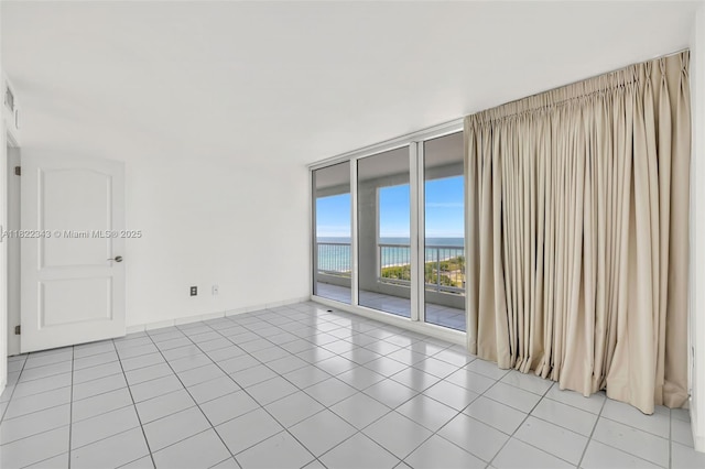 9341 Collins Ave Unit 705, Surfside, FL 33154 - spare room featuring expansive windows, a water view, and light tile patterned flooring