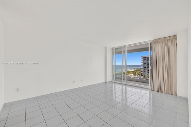 9341 Collins Ave Unit 705, Surfside, FL 33154 - spare room featuring expansive windows, light tile patterned floors, and a water view