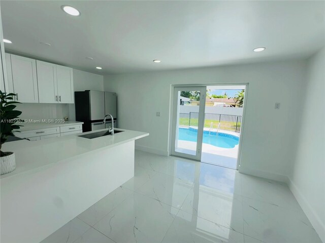 82 E 16th St, Hialeah, FL 33010 - kitchen featuring freestanding refrigerator, light marble finish flooring, recessed lighting, white cabinetry, and light countertops