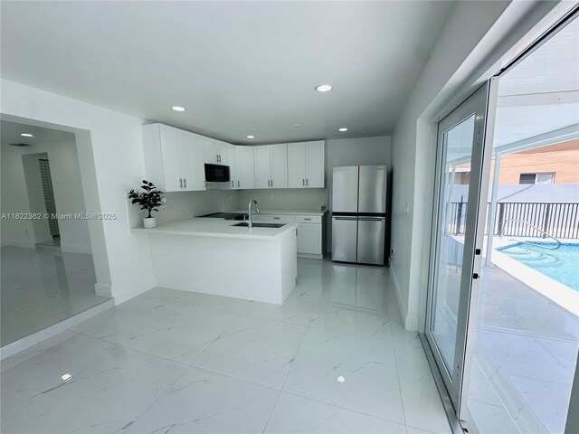 82 E 16th St, Hialeah, FL 33010 - kitchen featuring freestanding refrigerator, black microwave, a peninsula, light countertops, and white cabinets