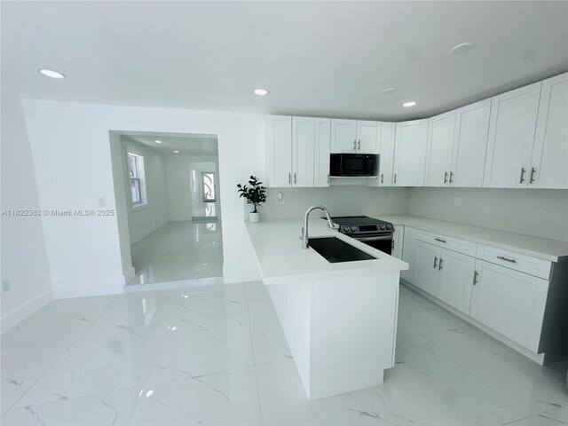 82 E 16th St, Hialeah, FL 33010 - kitchen featuring black microwave, light marble finish flooring, a peninsula, white cabinetry, and recessed lighting