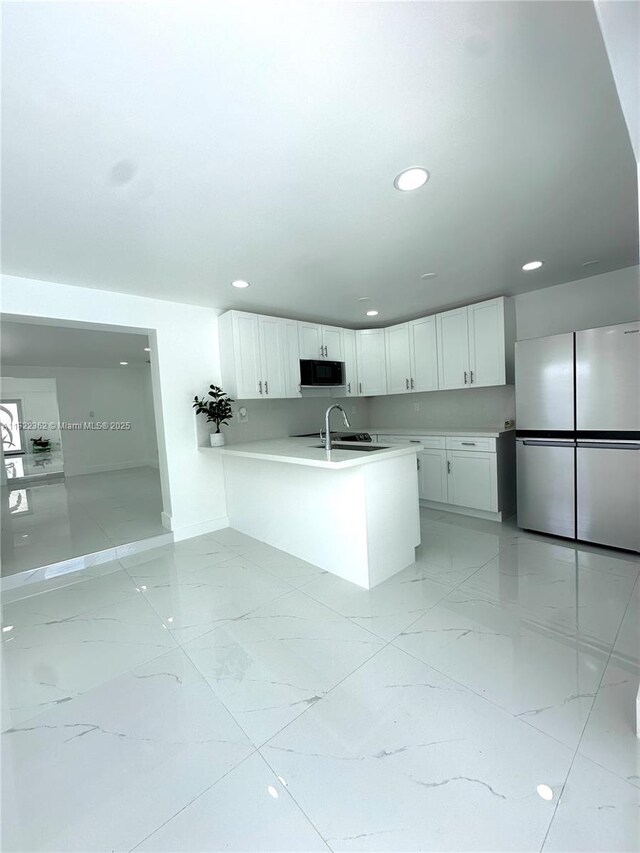 82 E 16th St, Hialeah, FL 33010 - kitchen featuring freestanding refrigerator, black microwave, a peninsula, light countertops, and white cabinetry