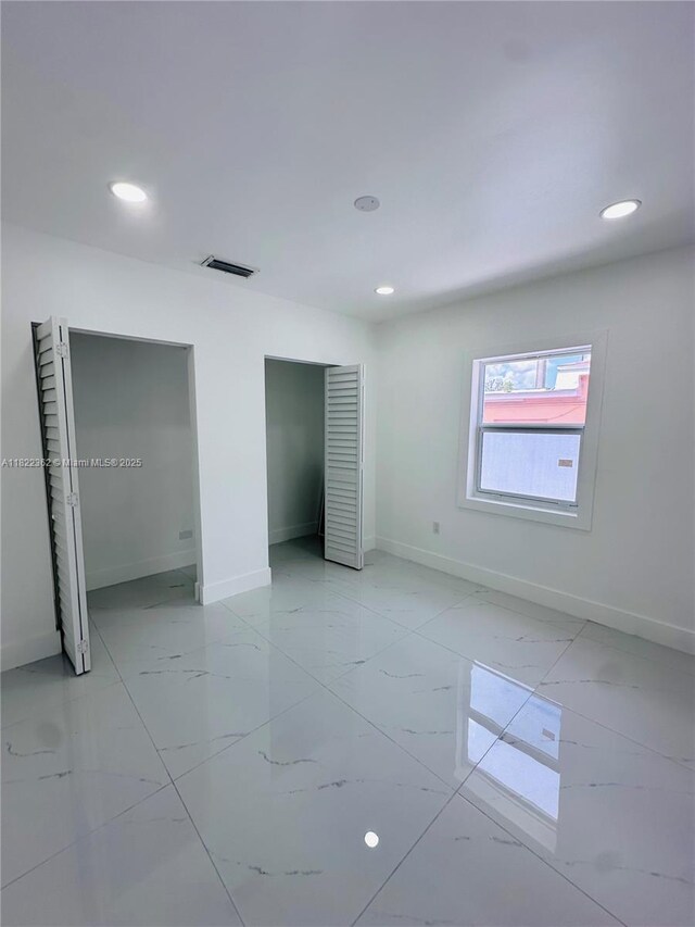 82 E 16th St, Hialeah, FL 33010 - unfurnished bedroom with two closets, recessed lighting, and light marble finish flooring