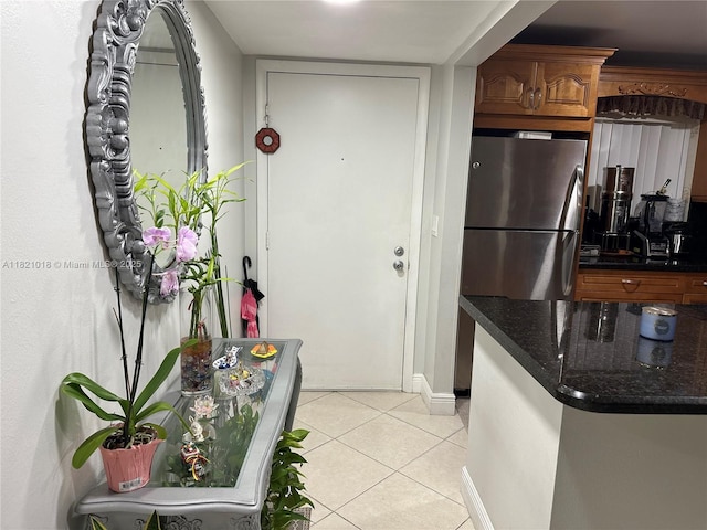 5160 Las Verdes Cir Unit 103, Delray Beach, FL 33484 - kitchen with freestanding refrigerator, light tile patterned floors, brown cabinets, and dark stone countertops