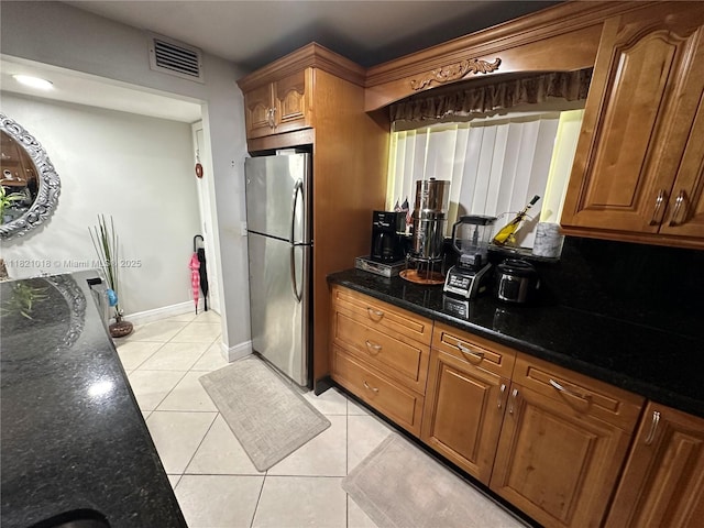 5160 Las Verdes Cir Unit 103, Delray Beach, FL 33484 - kitchen with freestanding refrigerator, light tile patterned flooring, dark stone counters, and brown cabinetry