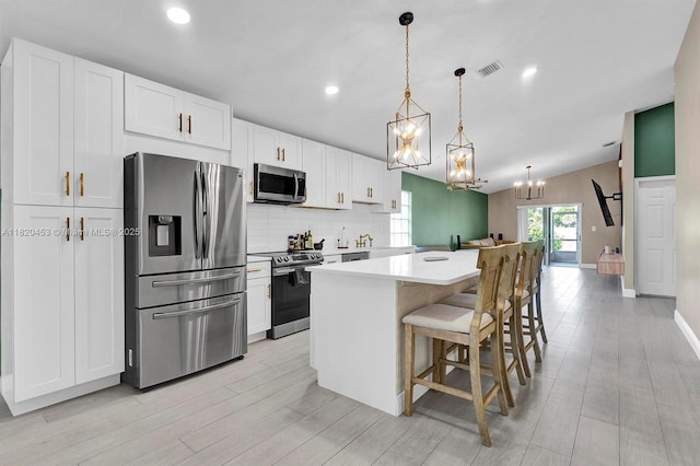 142 SW 204th Ave, Pembroke Pines, FL 33029 - kitchen with appliances with stainless steel finishes, a chandelier, a center island, white cabinetry, and decorative backsplash