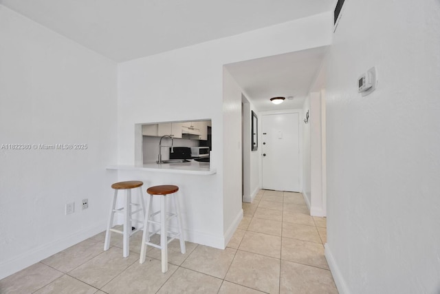 7403 SW 82nd St Unit 207N, Miami, FL 33143 - kitchen featuring a breakfast bar area, light countertops, light tile patterned floors, and a peninsula