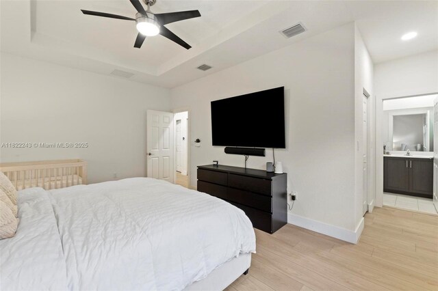 10129 W 32nd Ln, Hialeah, FL 33018 - bedroom with light wood finished floors, a raised ceiling, connected bathroom, and ceiling fan