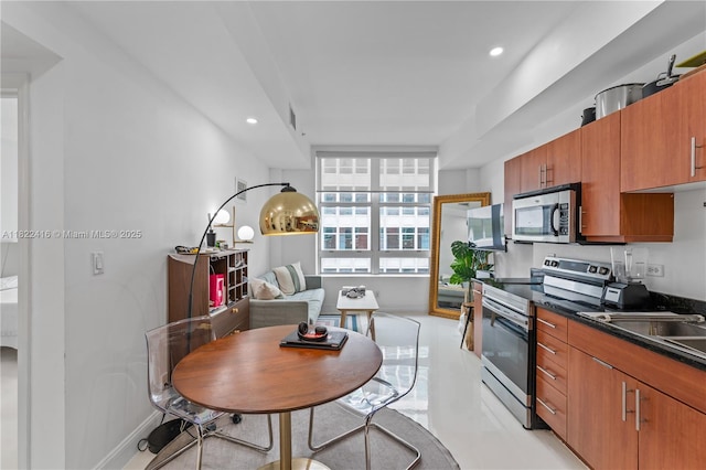 111 E Flagler St Unit 603, Miami, FL 33131 - kitchen featuring stainless steel appliances, dark countertops, brown cabinets, and recessed lighting