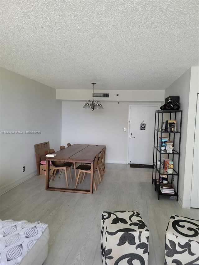 3300 NE 192nd St Unit 1008, Aventura, FL 33180 - dining room with a textured ceiling, light wood-style floors, and a chandelier