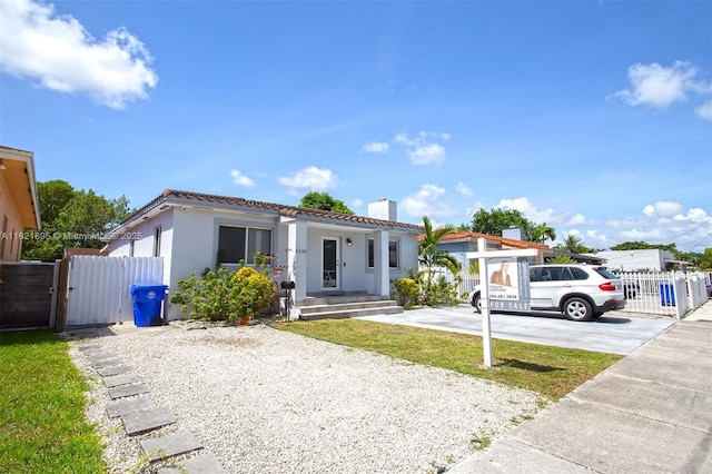 3430 NW 16th St, Miami, FL 33125 - mediterranean / spanish home with a gate, a chimney, a tiled roof, stucco siding, and driveway